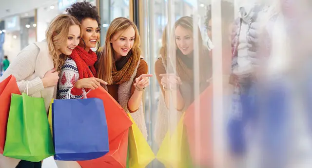 Ladies do holiday shopping and point into a window.