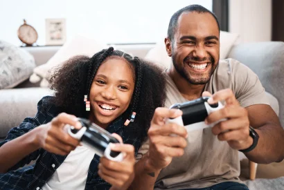 Father and Daughter sitting on couch and playing video games together