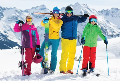 family with two children all in bright colored winter clothing excited to ski